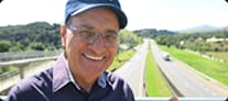 Pedro Trucão, apresentador do Pé na Estrada, usando boné azul e camisa cinza com logo Mobil em fundo escuro.