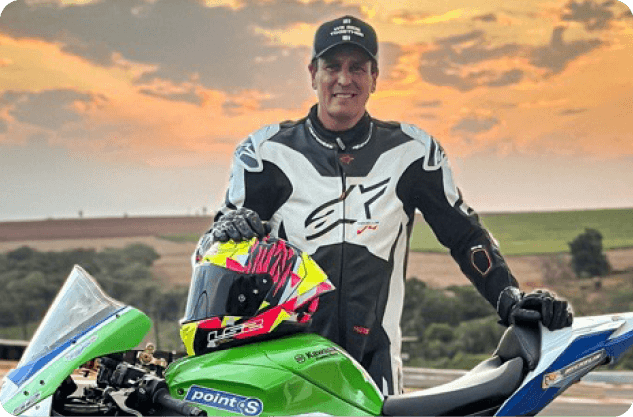 Leandro Melo usando boné e macacão Mobil Super Moto em ambiente externo com céu azul.