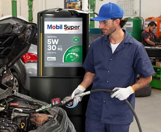 Mecânico abastecendo o motor de um carro com óleo Mobil Super em oficina automotiva.
