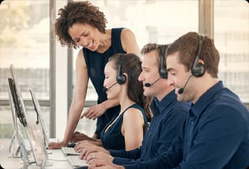 Equipe de atendimento de duas mulheres e dois homens com fones de ouvido trabalhando em computadores em uma central de suporte.