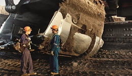 Duas pessoas em frente a equipamento de mineração