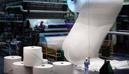 Indústria vista de dentro, com um rolo de celulose enrolado em uma máquina ilustrando o uso dos lubrificantes industriais Mobil